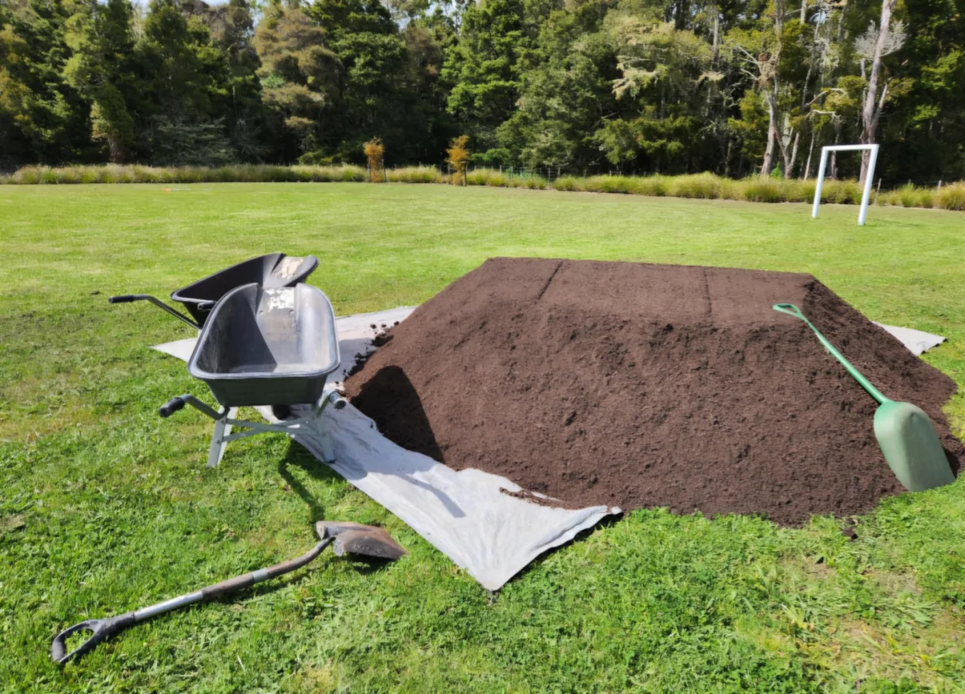 Wheelbarrow, spade and fresh garden soil ready for bed prep